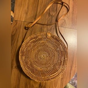 Brown rattan sling circle bag. Long strap with button closure.